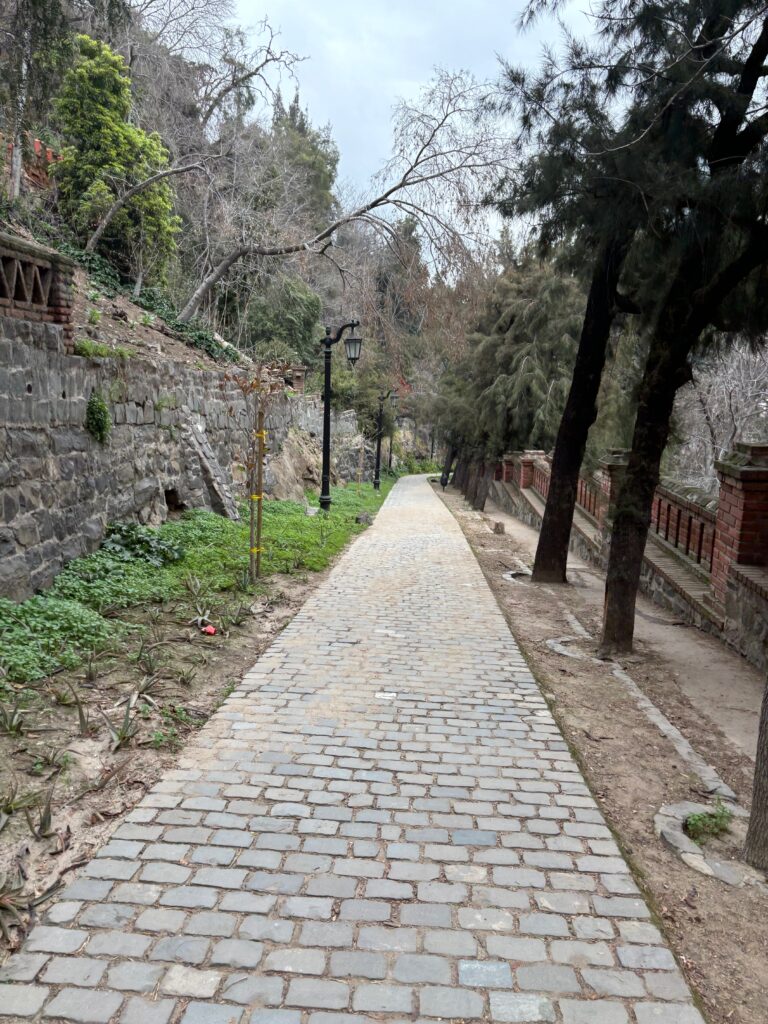 a stone path with trees and a stone wall