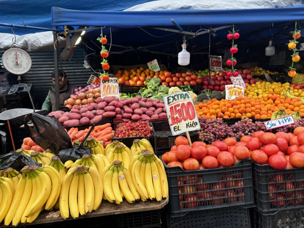 a fruit stand with signs and vegetables