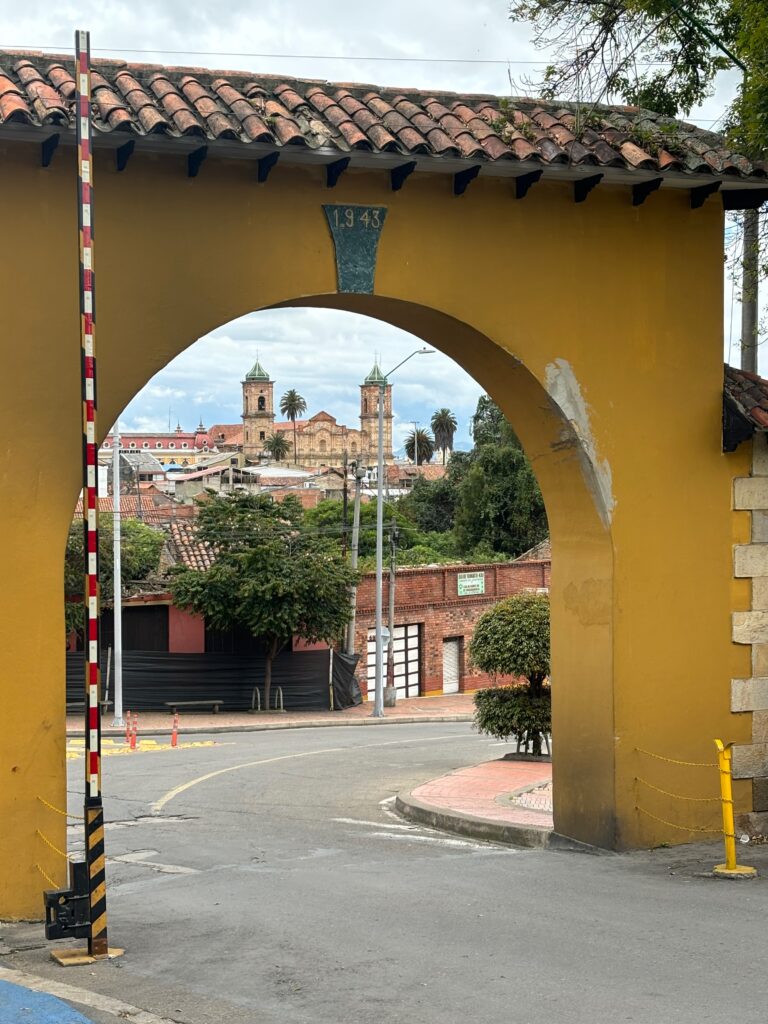 a yellow archway with a road and buildings in the background