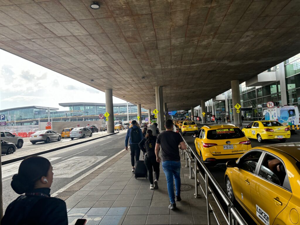 a group of people walking on a sidewalk with cars and people walking