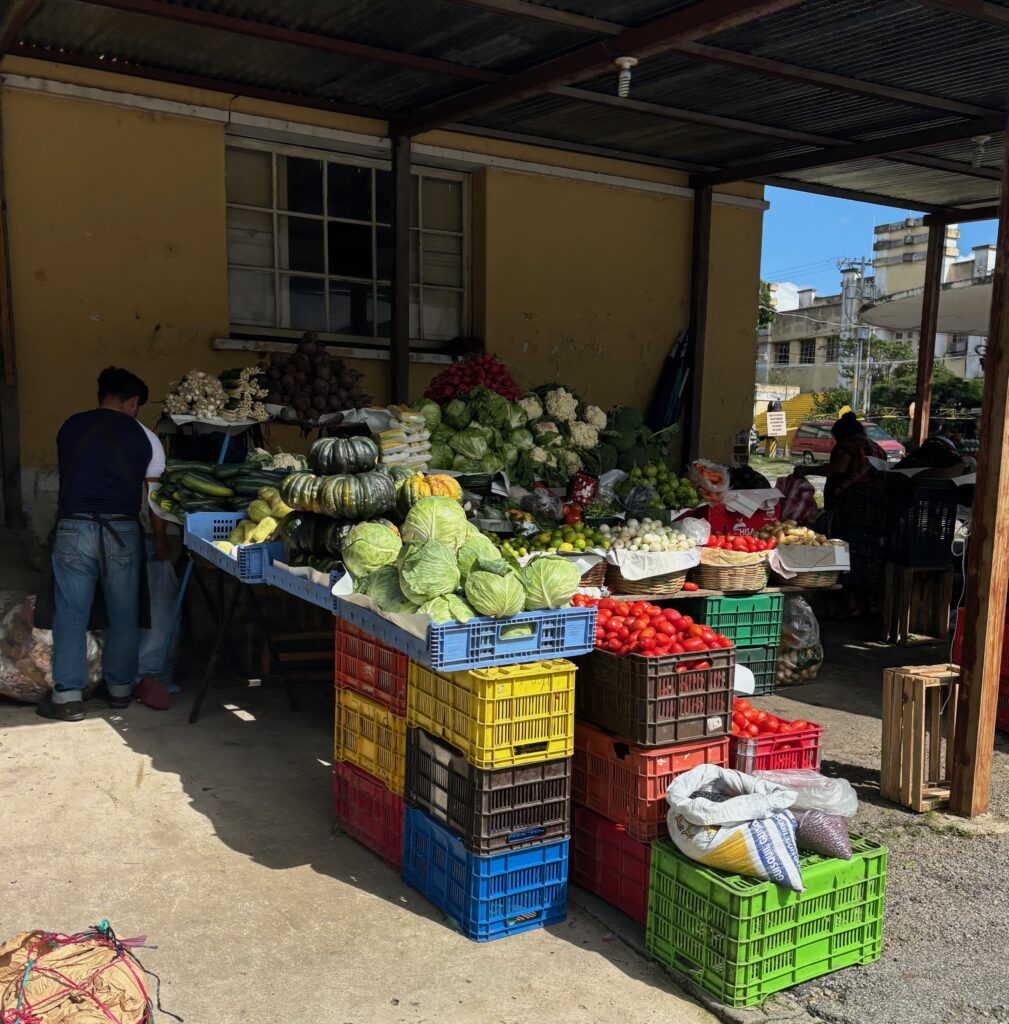 a fruit stand with many crates of vegetables