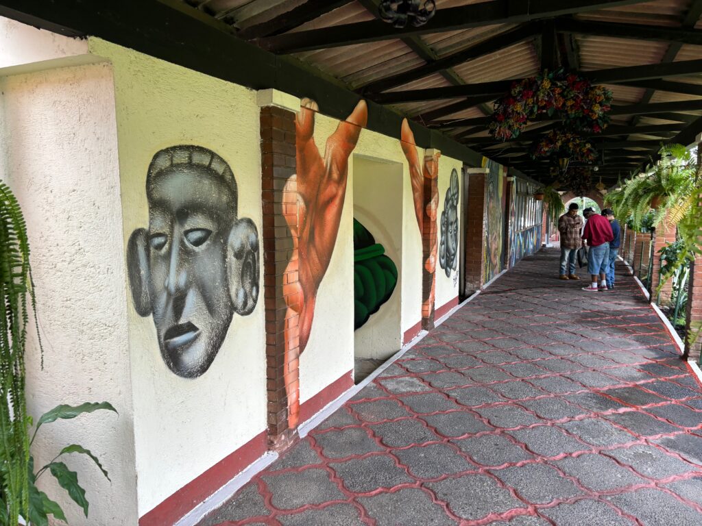 a group of people walking on a walkway with a mural on the wall