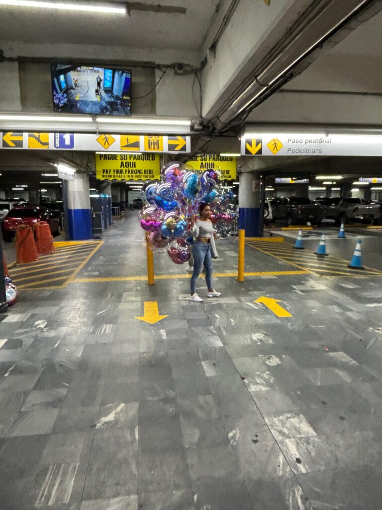 a woman standing in a parking lot holding balloons