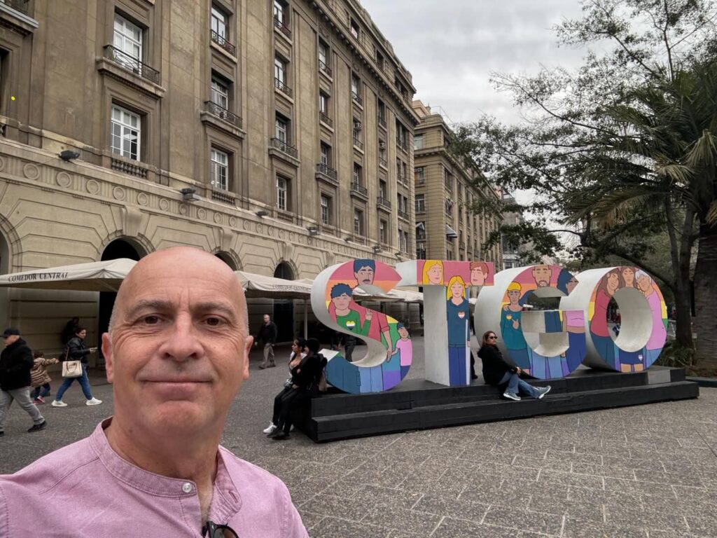 a man taking a selfie in front of a large sign