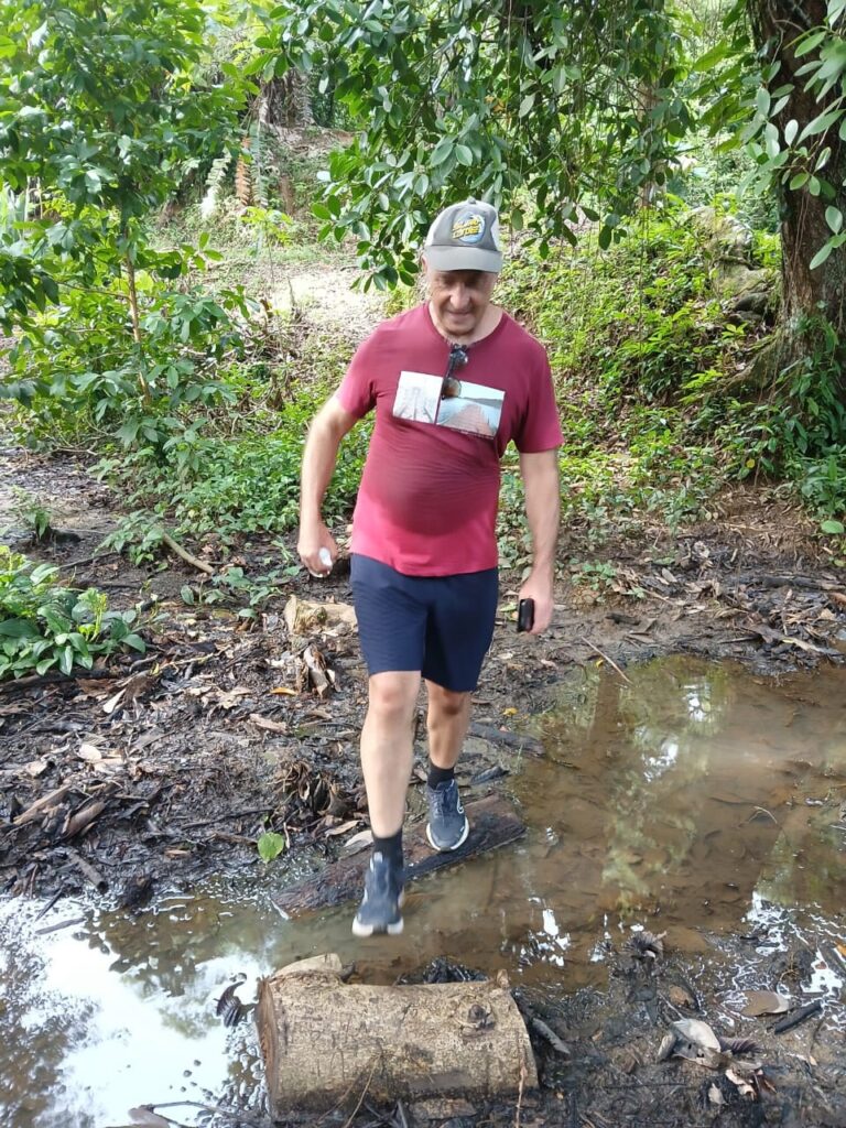 a man walking on a log in a muddy stream