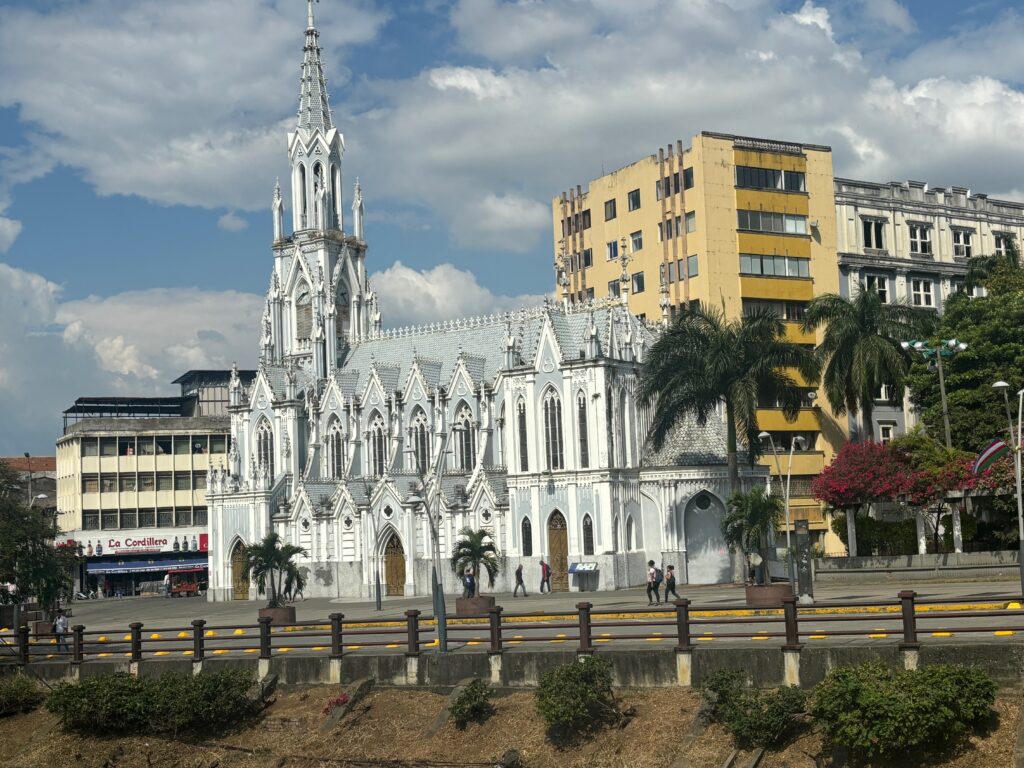 a white church with a steeple and palm trees