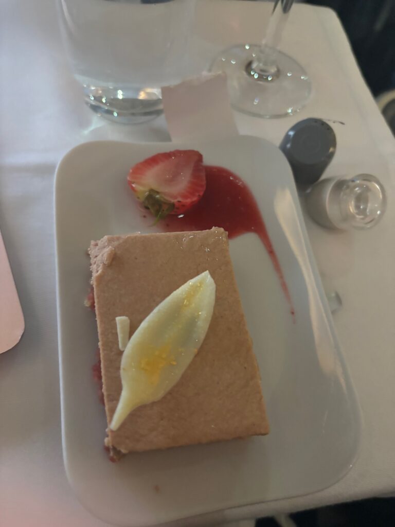 a plate of dessert with a strawberry and a piece of cake