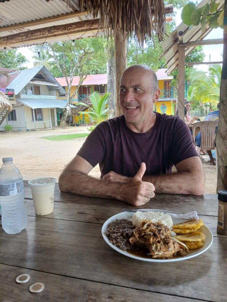 a man sitting at a table with a plate of food and a bottle of water