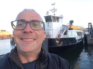 a man taking a selfie in front of a boat