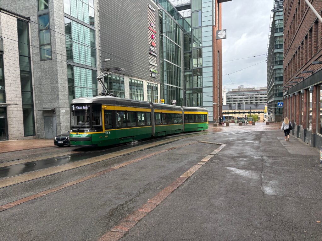 a green and yellow train on a street