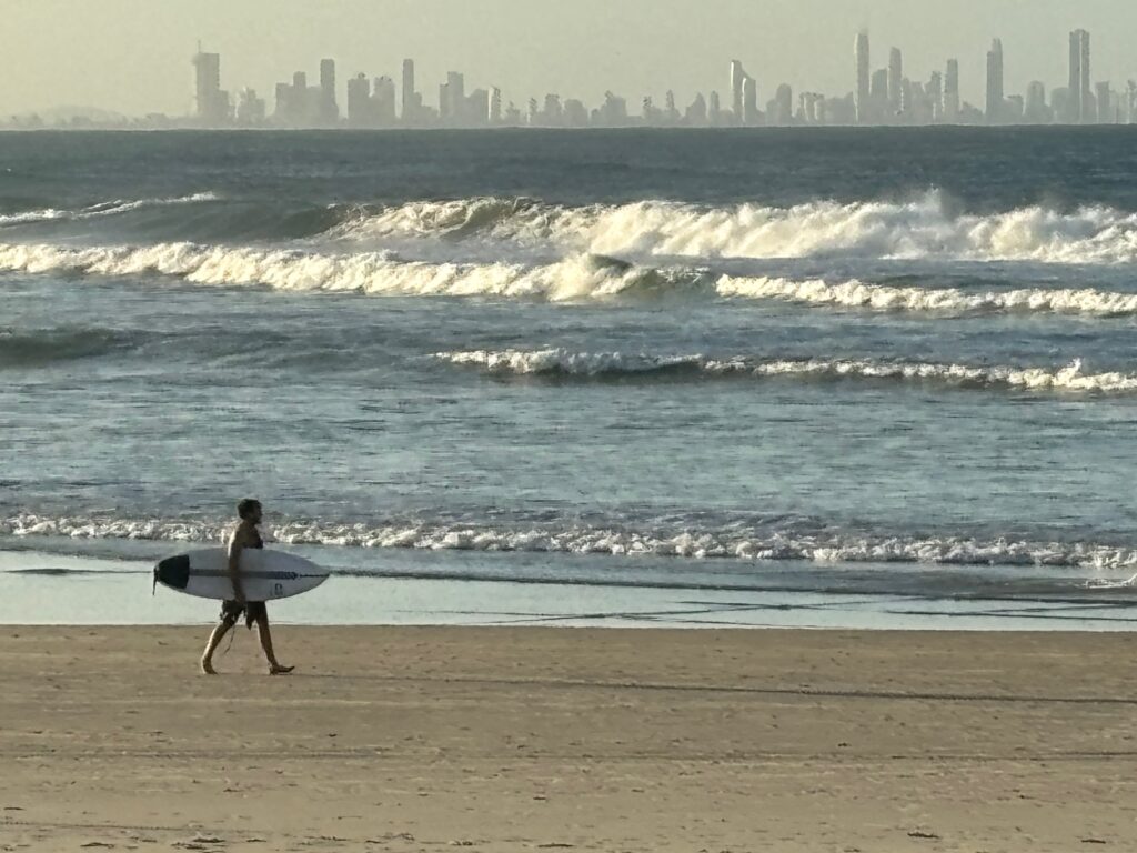 a man walking on a beach with a surfboard