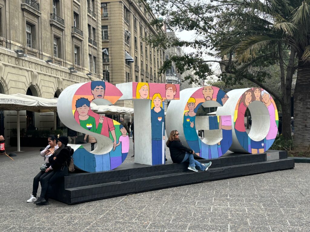 a group of people sitting on a bench in front of a large sign