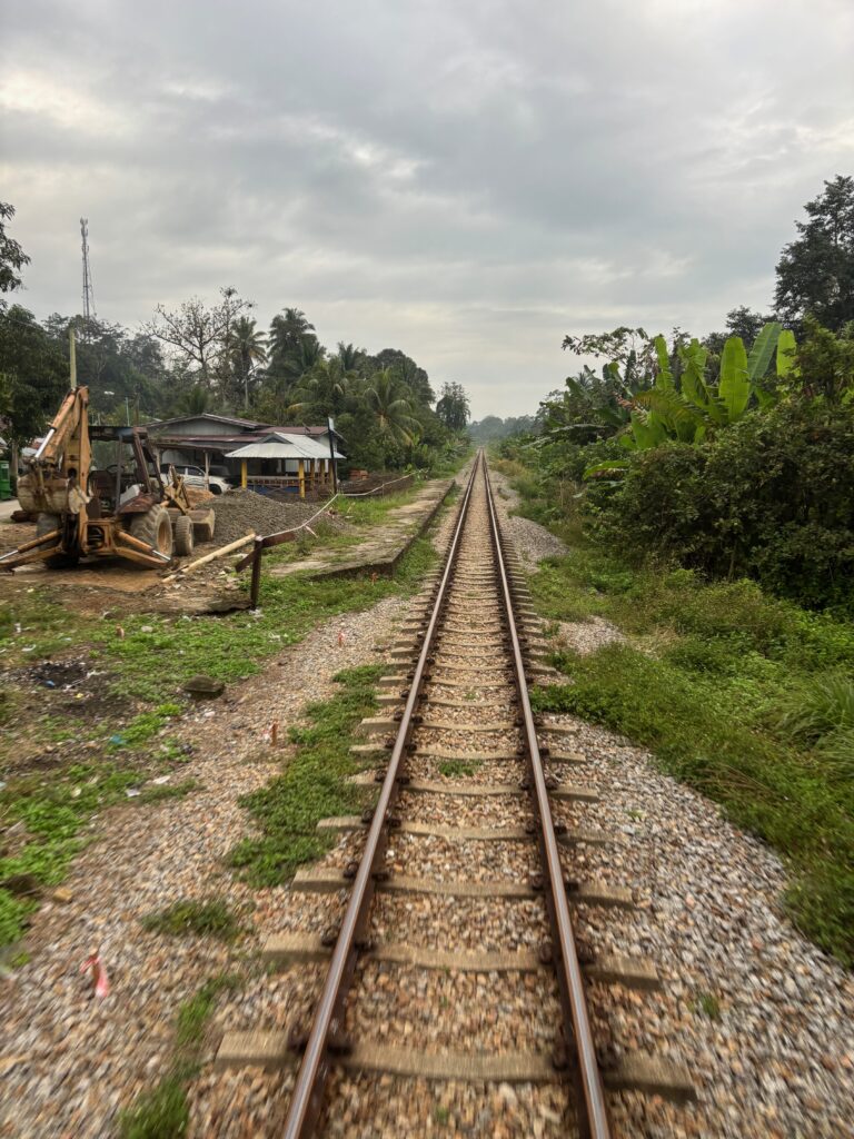 train tracks with a tractor and a building in the background