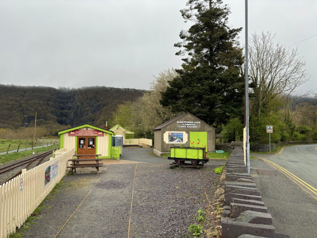 a small building with a train car and a tree in the background