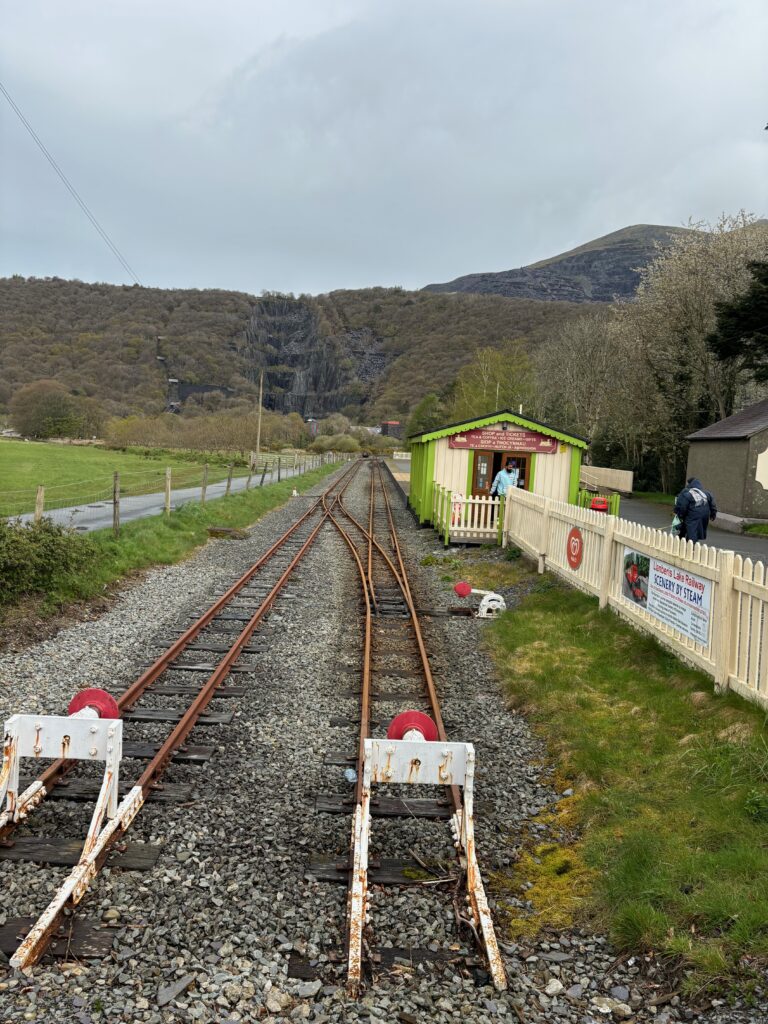 a train tracks with a small shed and trees in the background