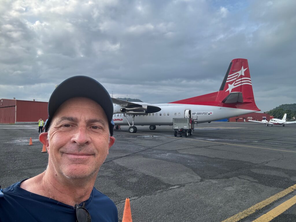 a man taking a selfie in front of an airplane