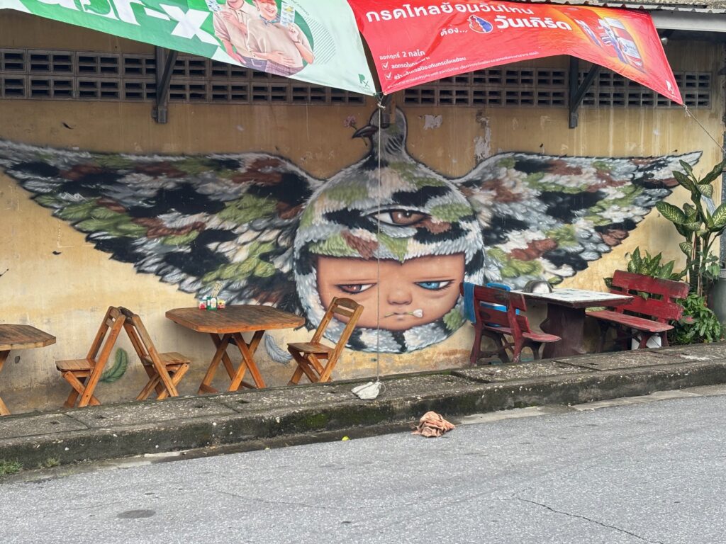 a mural of a bird with wings and a table and chairs under a canopy