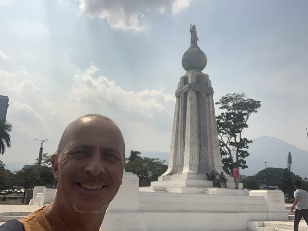 a man taking a selfie in front of a statue