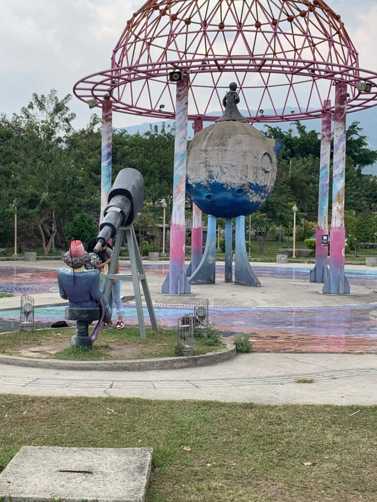 a statue of a man looking through a telescope in a park