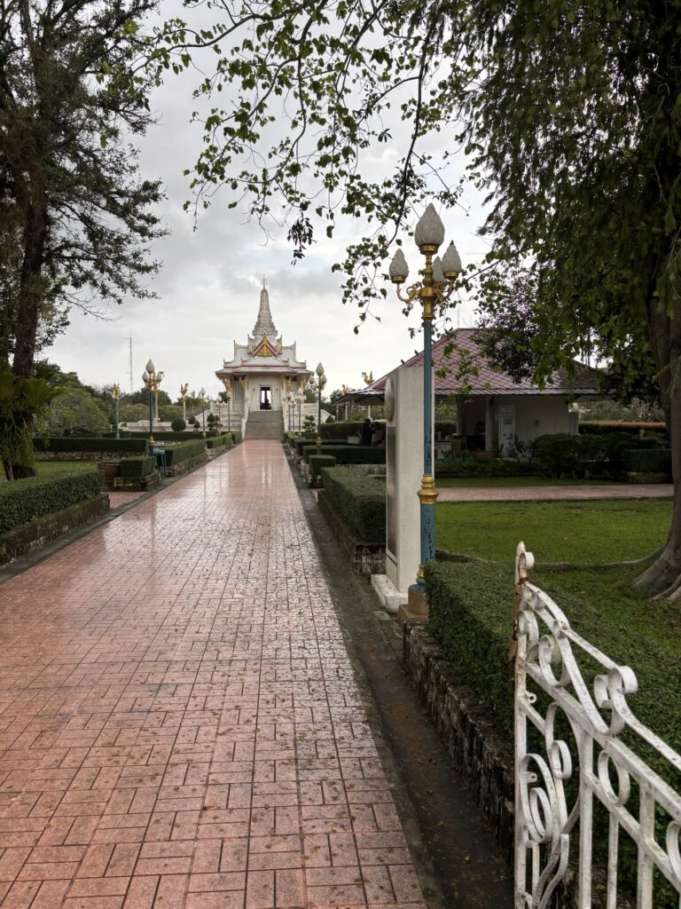 a brick path with a white building and trees