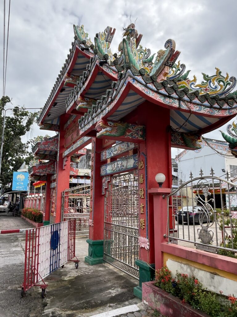 a gate with a red gate and a red gate with a red gate and a white gate with a red gate and a blue gate with a white gate and cars and a blue sky with clouds