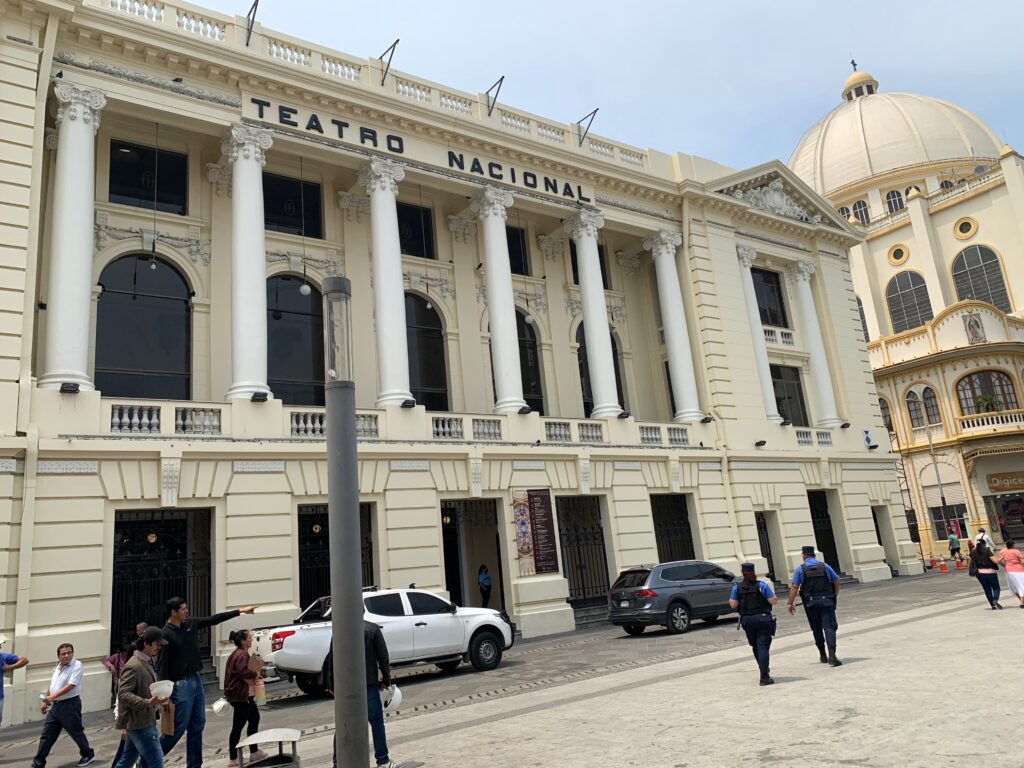 a building with columns and people walking in front of it