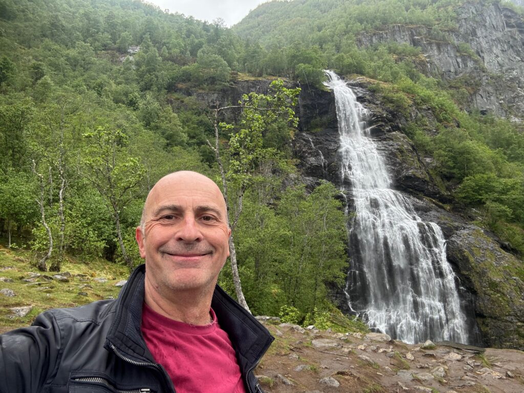 a man taking a selfie in front of a waterfall