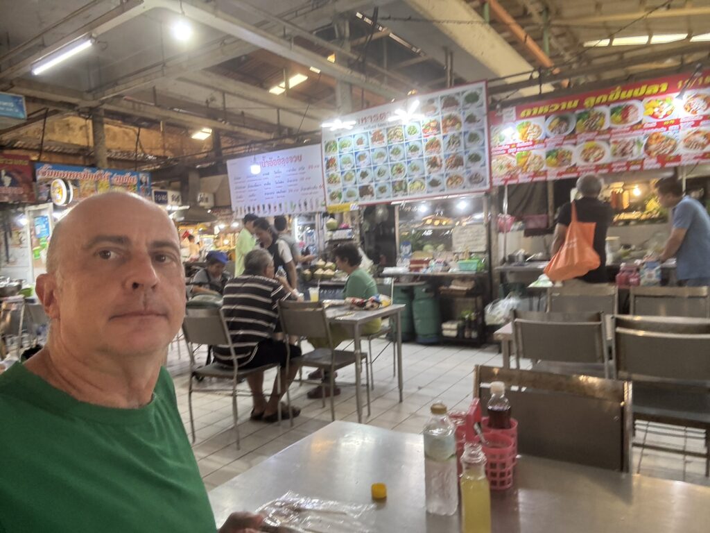 a man sitting at a table in a food market