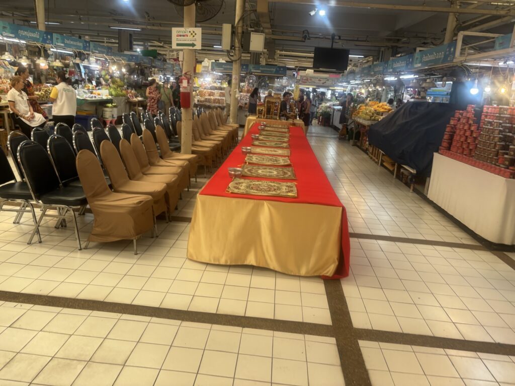 a long table with red cloth and plates on it in a market