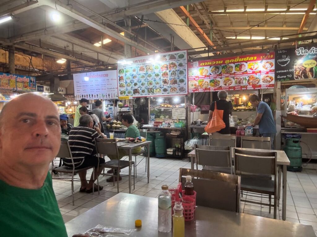 a man taking a selfie at a food market