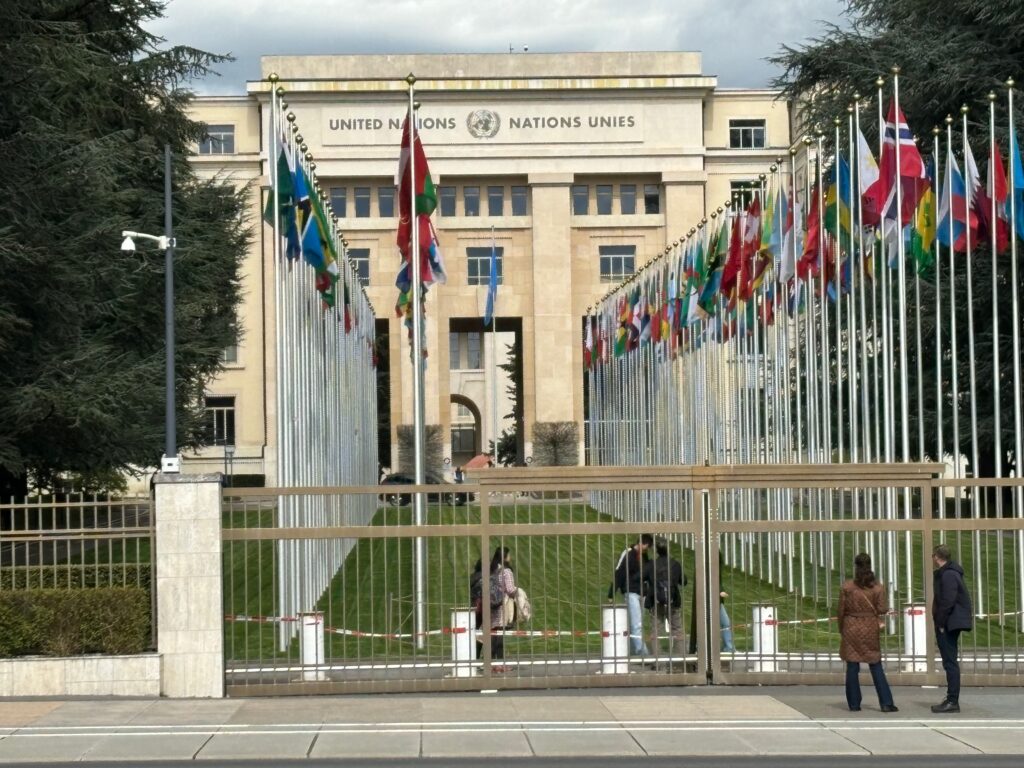 a group of people standing outside of a building with flags