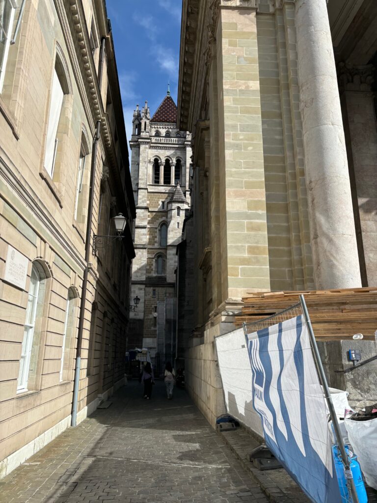 a stone alleyway between buildings with a tall tower