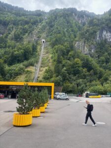 a woman walking in a parking lot with a yellow building and trees