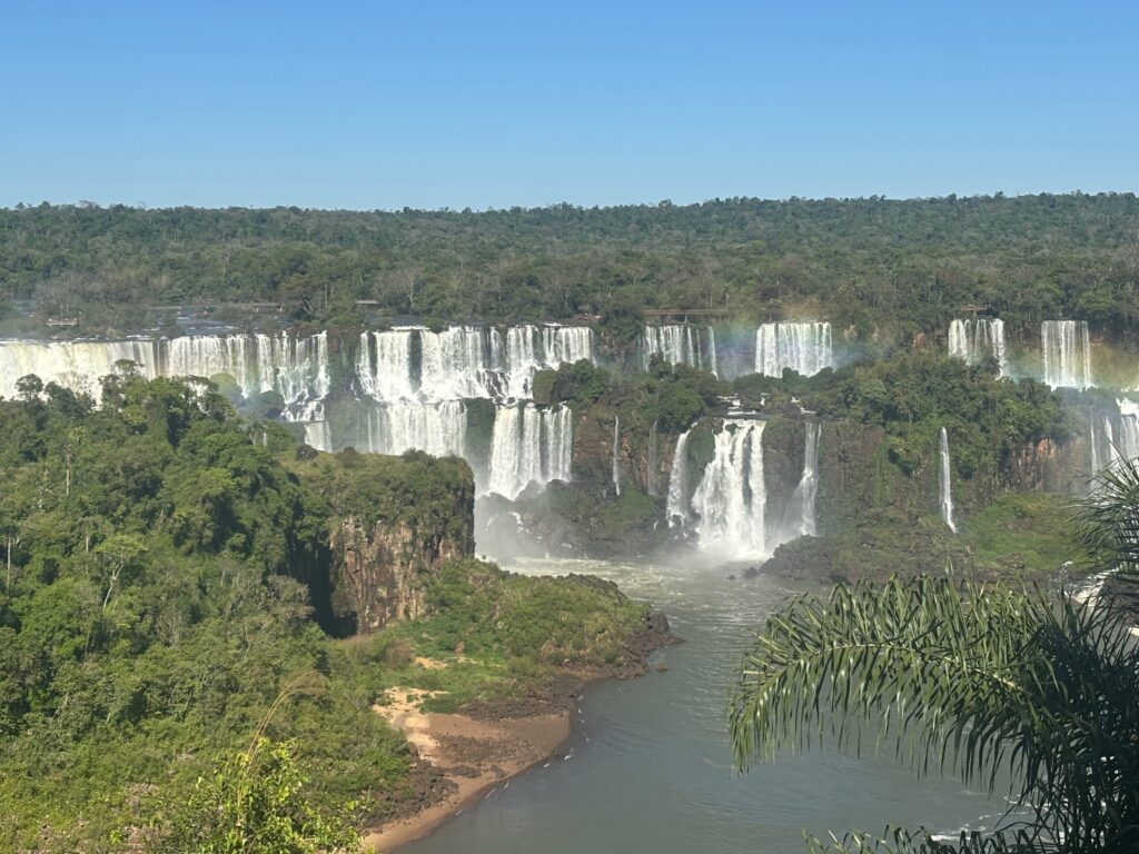 a waterfall with trees and a rainbow