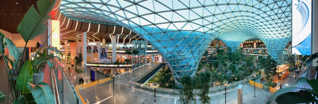 a glass structure with a walkway and trees