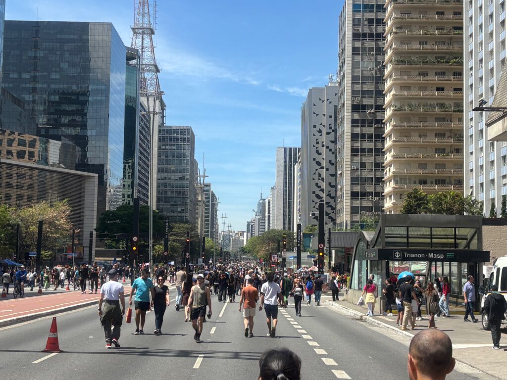 a group of people walking on a street with tall buildings