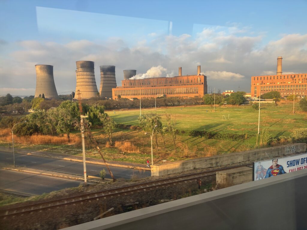 a factory with smoke stacks and grass and trees