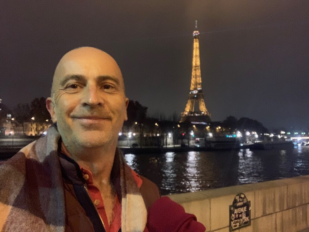 a man taking a selfie with a tall tower in the background