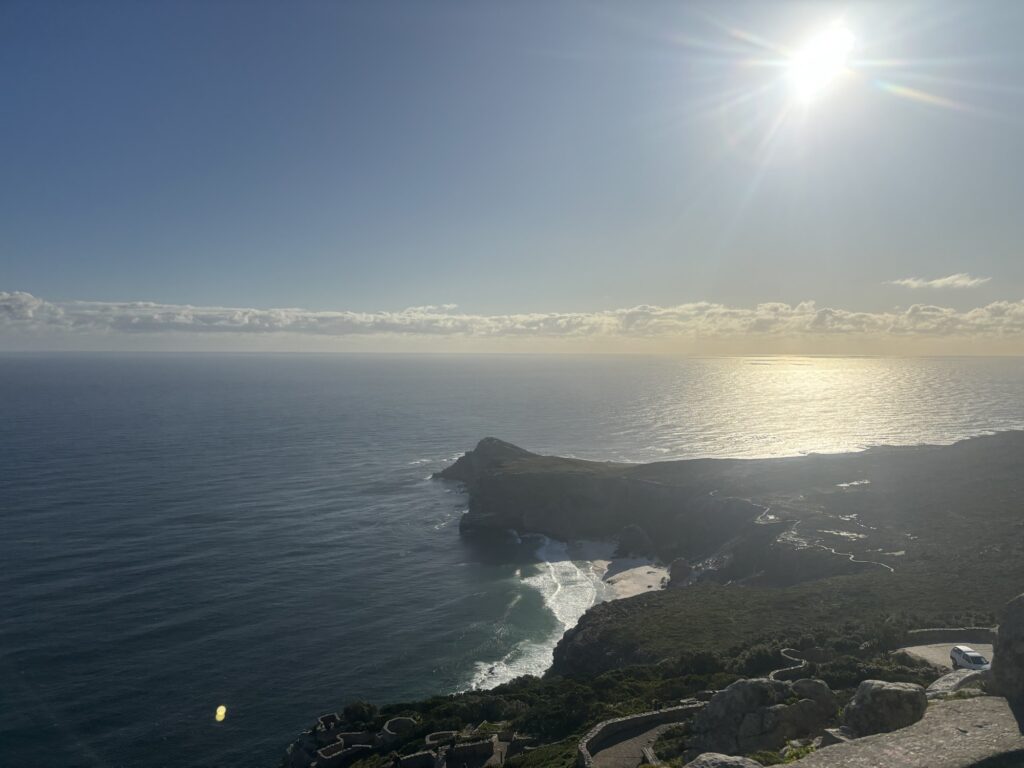 a rocky coastline with a body of water and the sun