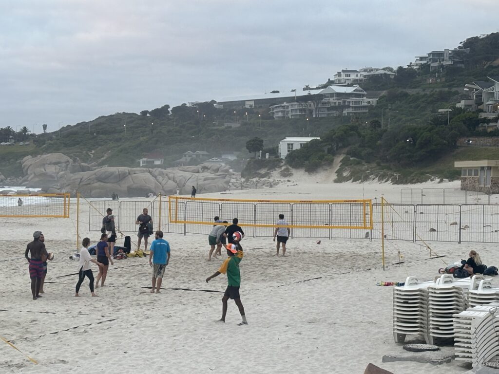 a group of people playing volleyball on a beach