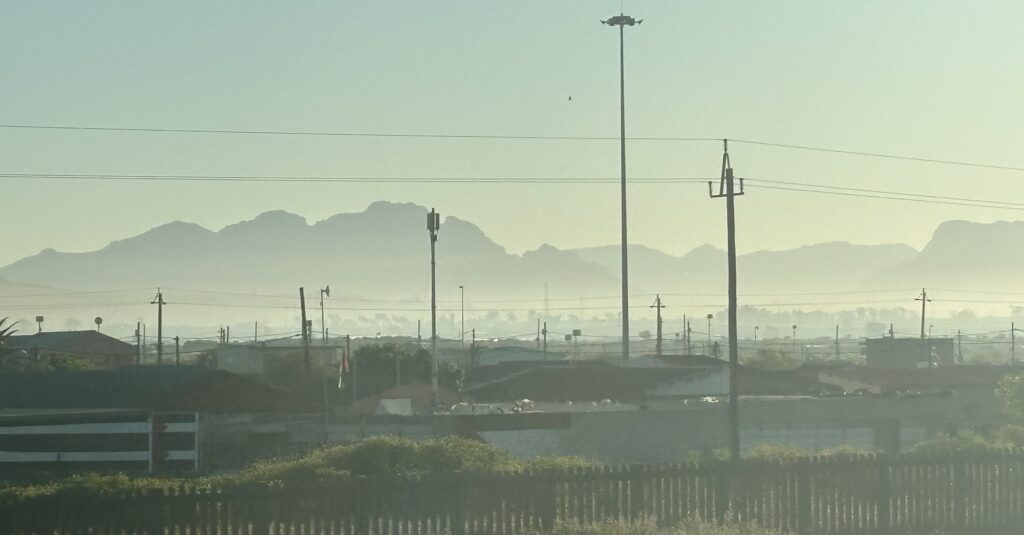 a city landscape with power lines and mountains in the background