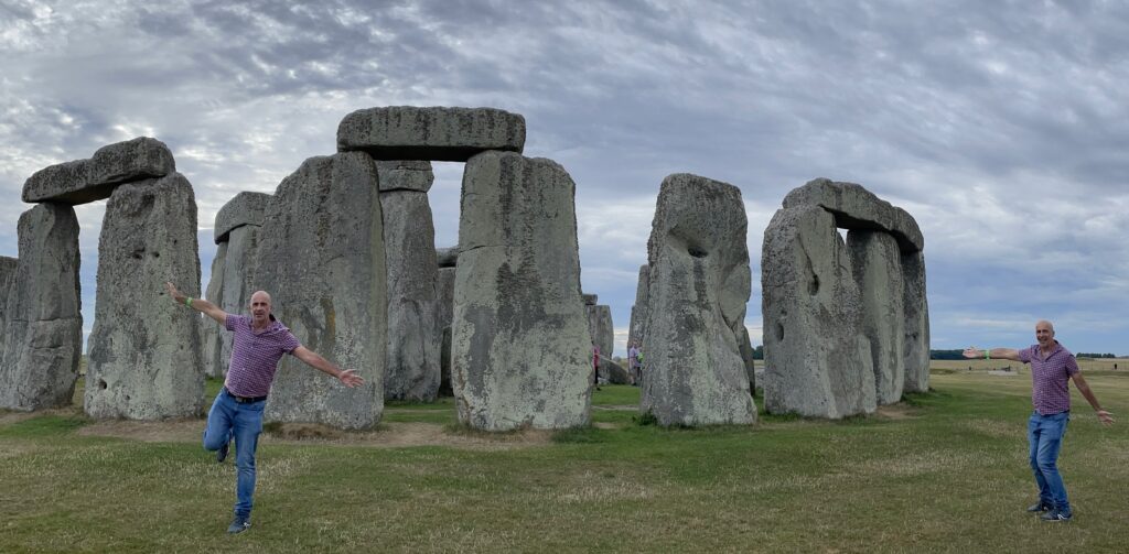 Un hombre se encuentra frente a una gran estructura de piedra con Stonehenge al fondo.