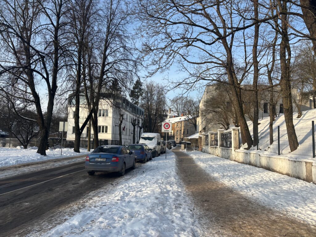 a snow covered street with cars parked on it