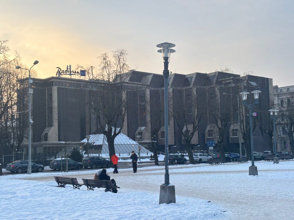 a snow covered park with people and cars in the background