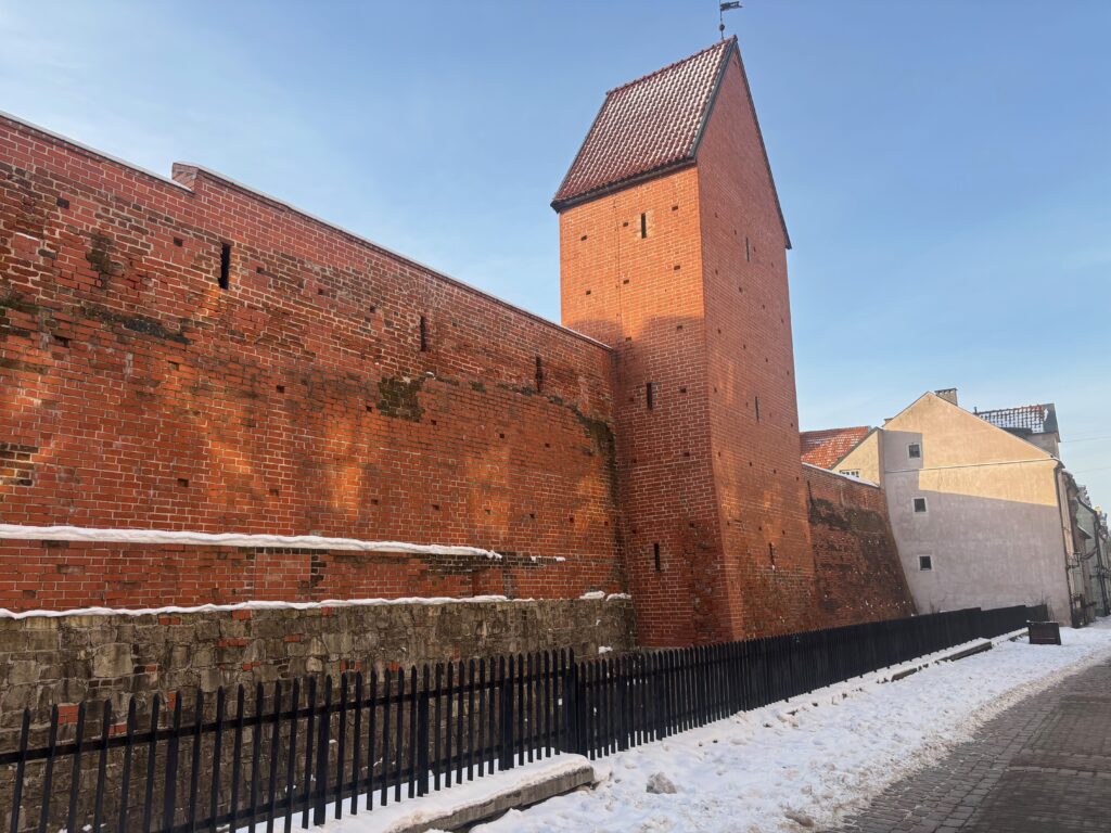 a brick wall with a tower and a fence