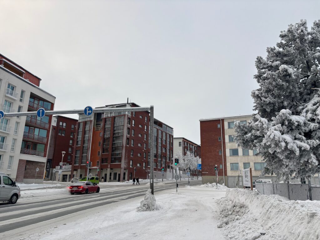 a snowy street with buildings and trees