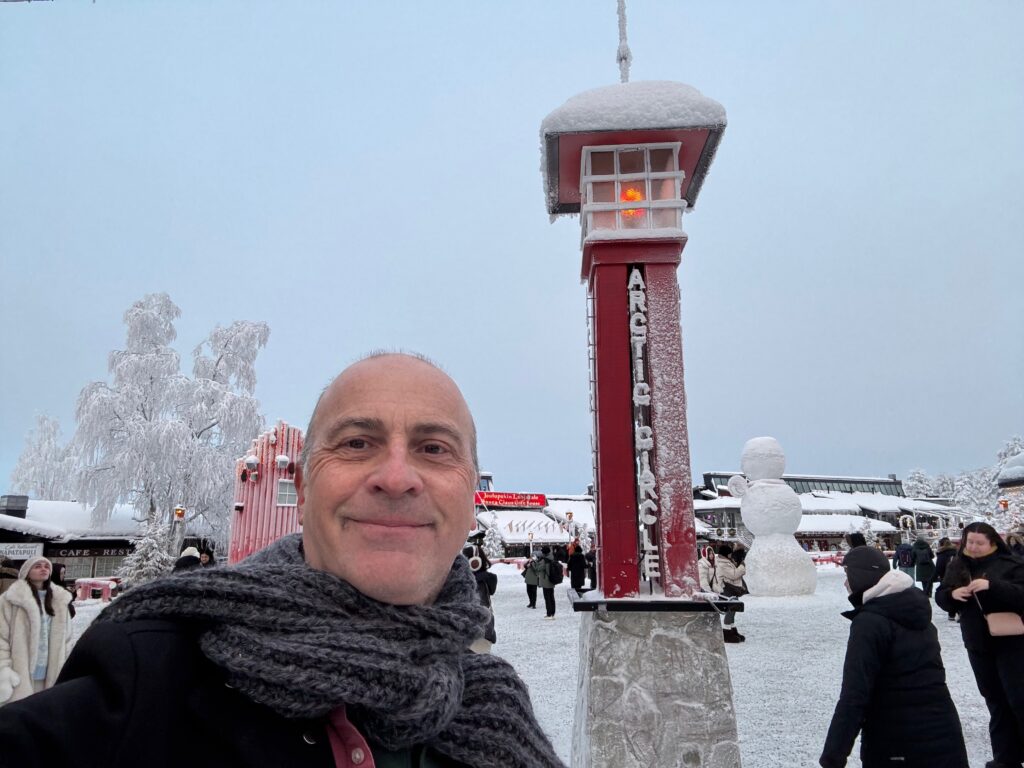 a man smiling in front of a red tower