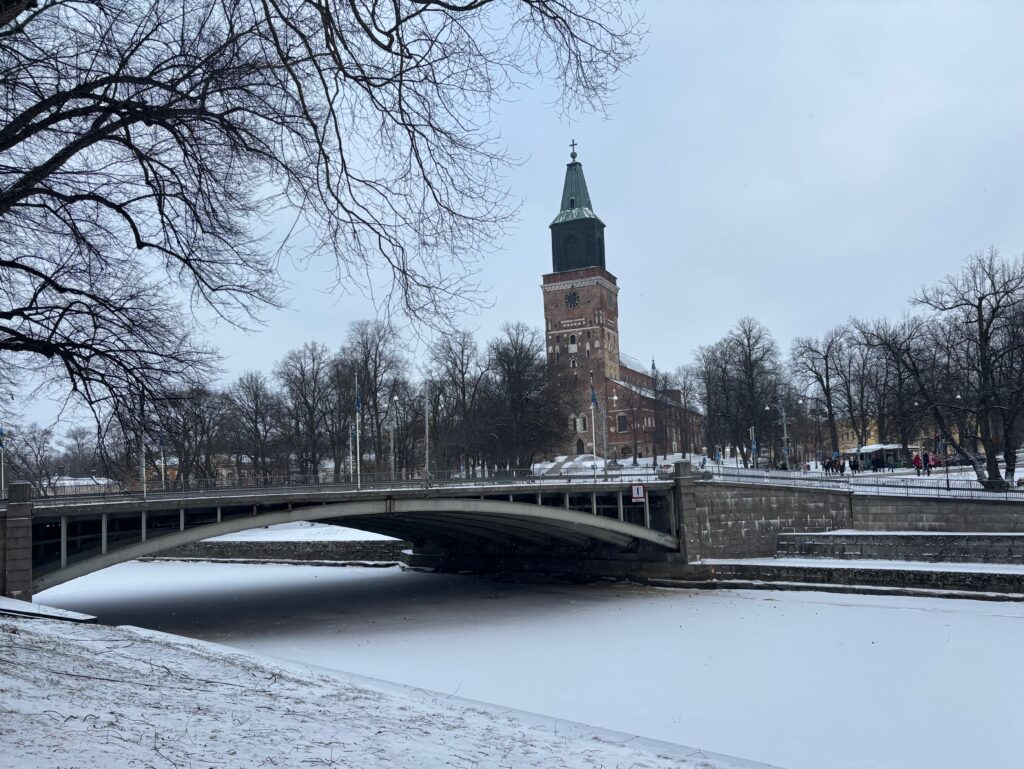 a bridge over a frozen river with a tower in the background