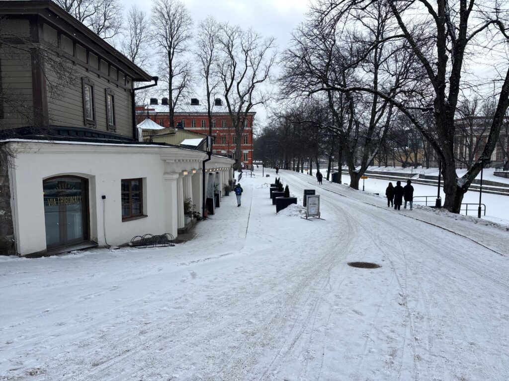 a snow covered street with buildings and people walking