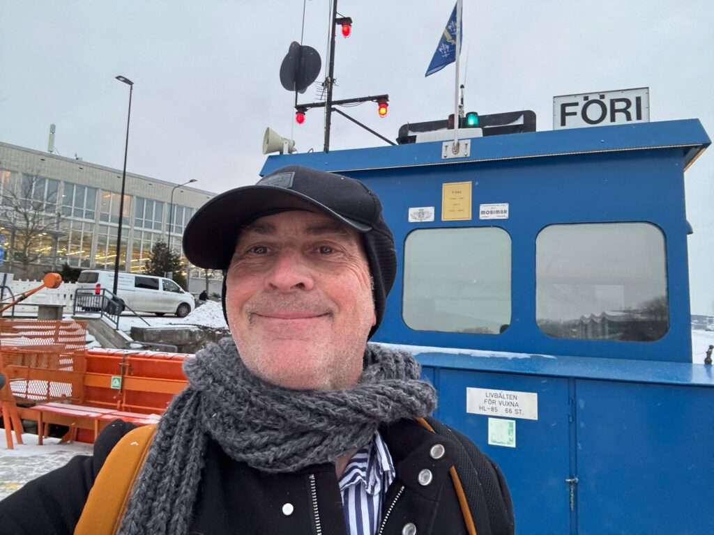 a man wearing a hat and scarf standing in front of a blue bus